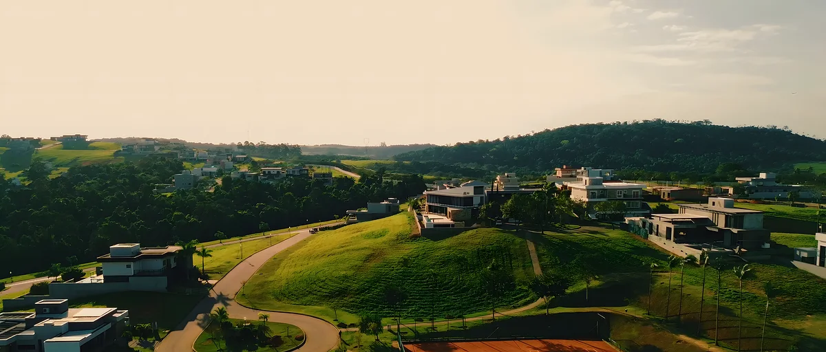 Ruas e casas do condomínio vistas do alto, entre gramados e árvores