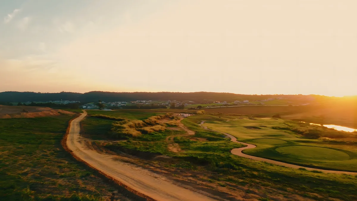 O fairway aberto ao pôr do sol, com o lago ao fundo