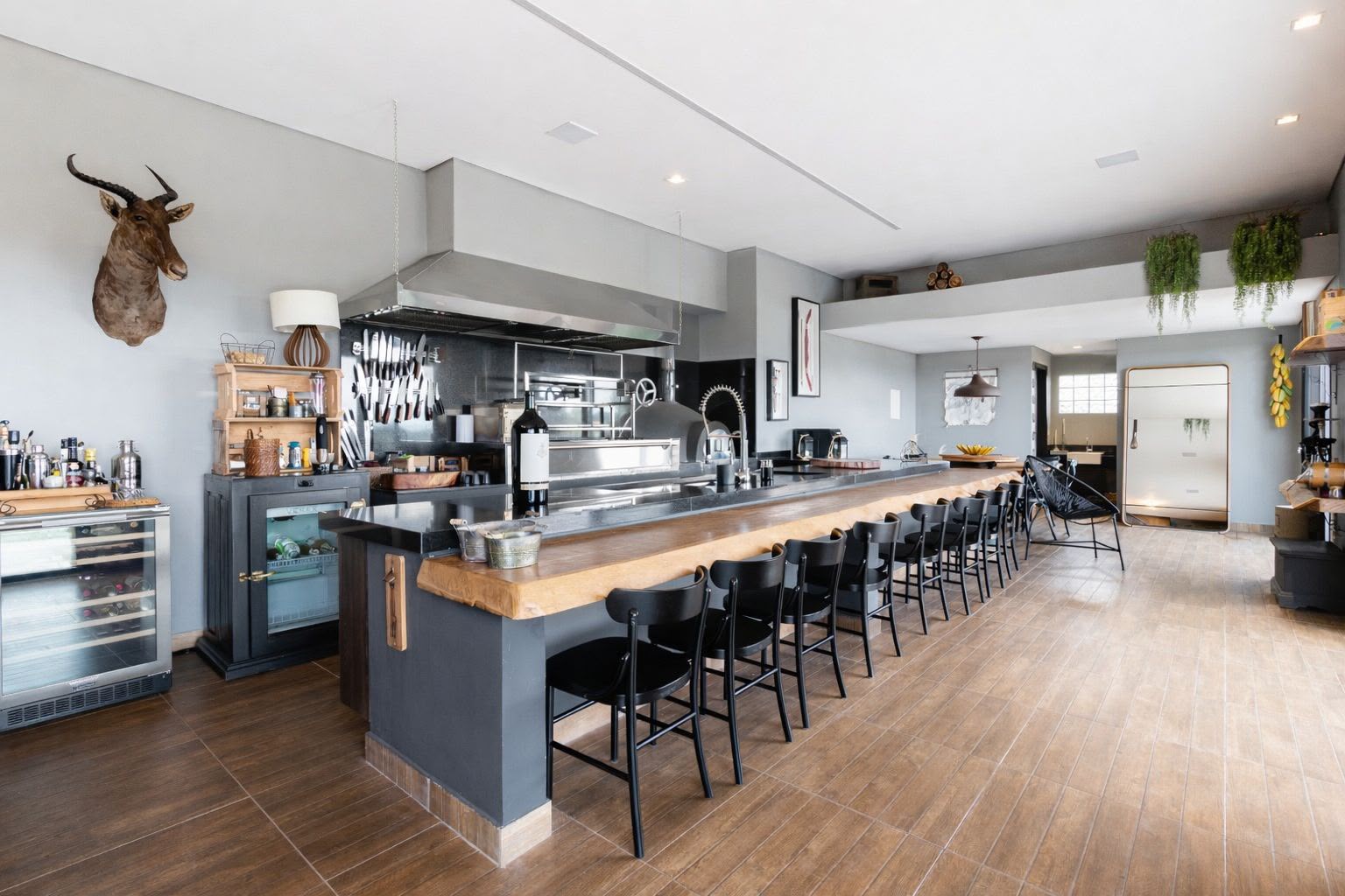 Bar da área gourmet com bancada corrida em madeira e vista para o terraço