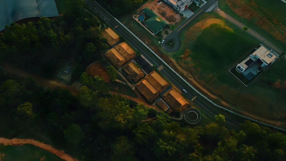 Centro hípico visto do alto, com picadeiros cobertos e pistas entre o verde