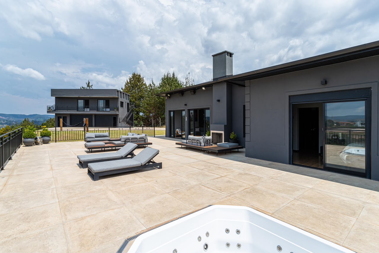 Terraço com jacuzzi e espreguiçadeiras diante da vista aberta das montanhas