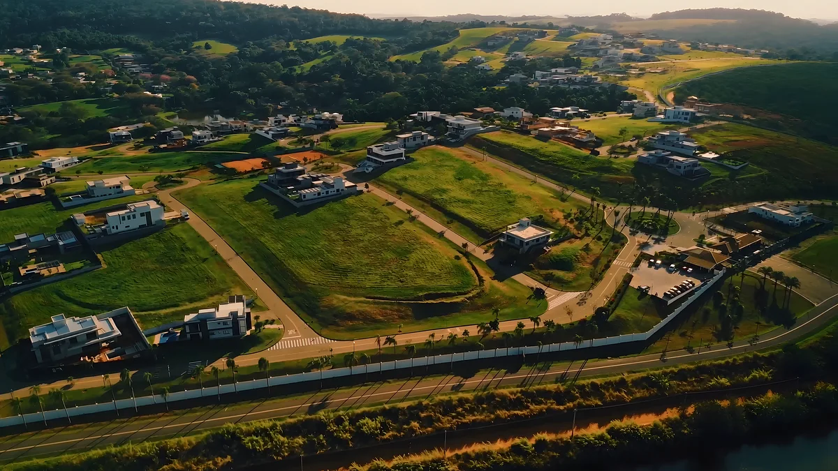 O terreno gramado entre árvores, ao lado da via do condomínio